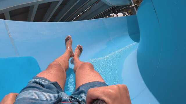 Man having fun and sliding down in a water slide, slow motion