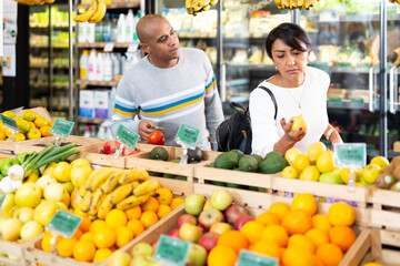 Married couple choosing fruits in grocery store