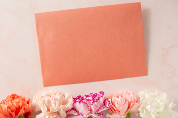 letter with carnations on pink marble background