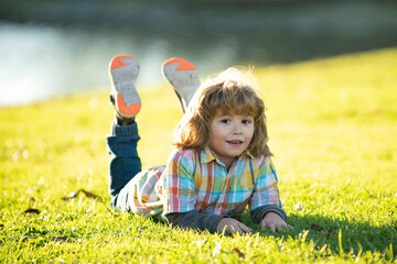 Child outdoor. Kid in park. Spring Boy lying on grass. Summer walk. Children adaptation.