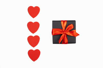 Black gift box with red bow isolated on white with red hearts. Symbol of love. Shopping concept.