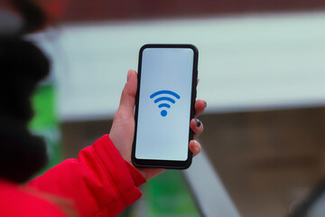 Free internet in the supermarket. Woman holds a mockup of a smartphone with an icon on a white screen against the background of the escalator in the mall.