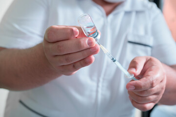 closeup to the hands of a latin man holding a syringe and medicinal liquid to be injected as a vaccine