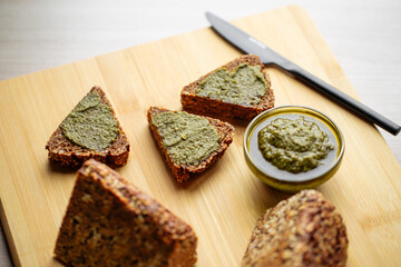 Closeup on sliced triangle flourless diet grain bread spread with pesto sauce