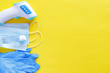 Coronavirus protection concept flat lay. Non-contact infrared body thermometer, latex gloves,...
