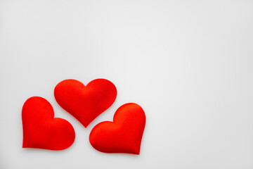 Three textured red hearts on top of each other on a white or gray background: place for text, St. Valentine's Day background, minimalism 