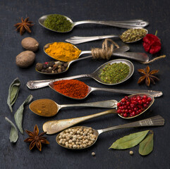 Various spices spoons on black table. Top view with copy space