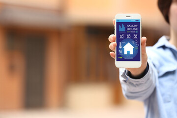 Woman using application of smart home automation outdoors