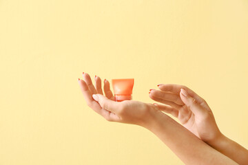 Female hands with natural lip balm on color background