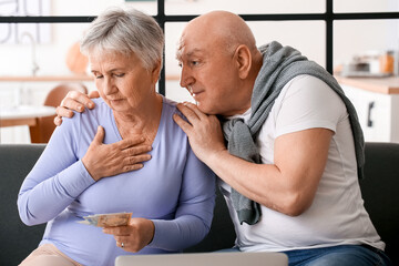 Stressed senior couple counting money at home