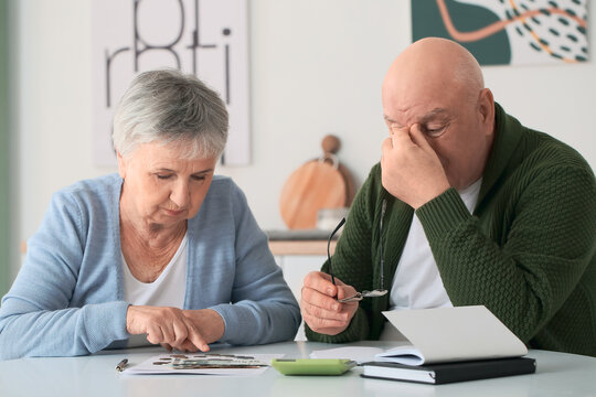 Stressed senior couple counting money at home - Powered by Adobe