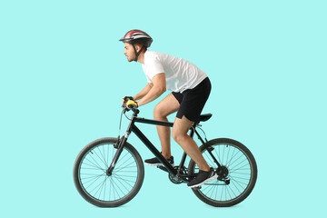 Obraz premium Male cyclist riding bicycle on color background