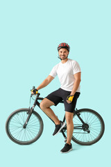 Naklejka premium Male cyclist with bicycle on color background