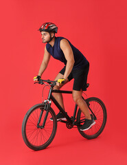 Fototapeta premium Male cyclist riding bicycle on color background