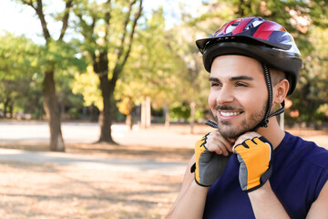 Male cyclist putting on helmet outdoors