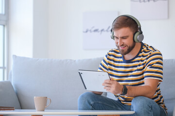 Young man with tablet computer and headphones at home