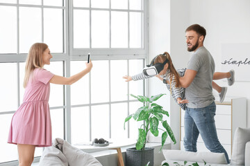 Parents and daughter with virtual reality glasses at home