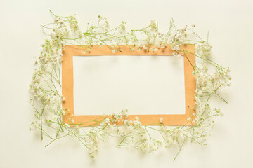 Beautiful flowers and blank frame on light background