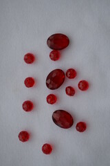 Large red beads scattered on a white background. Materials for needlework.