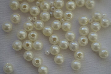 White round beads scattered on a white background. Materials for needlework.