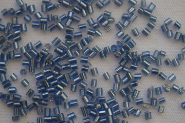 Blue beads scattered on a white background. Materials for needlework.
