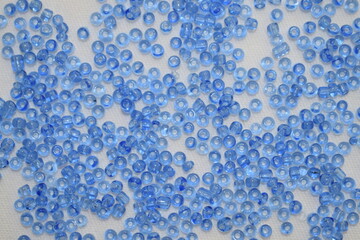 Blue beads scattered on a white background. Materials for needlework.