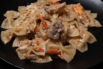 Macaroni in a black ceramic plate on a black table