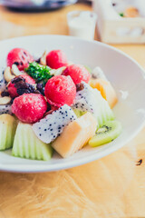 White bowl of fresh healthy fruit salad on wooden background