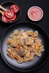 Macaroni in a black ceramic plate on a black table
