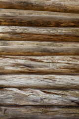 the texture of the wall of an old log house made of cylindrical logs without nails of a wooden house of a hut.