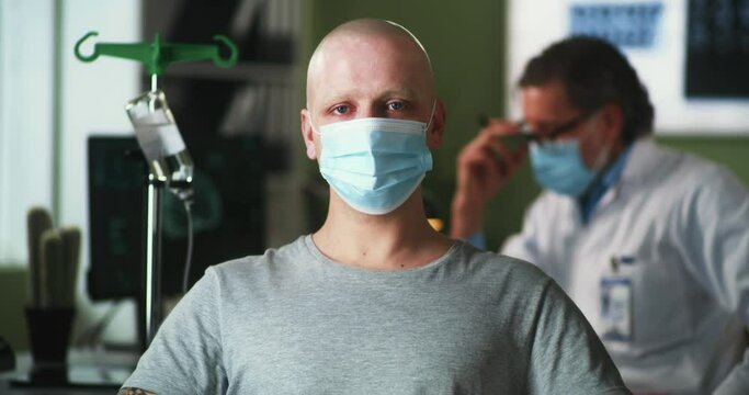 Bald man in mask looking at camera during chemotherapy