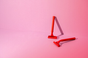 Red disposable razor on pink background, copy space