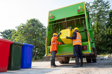 Two refuse collection workers loading garbage for trash removal.