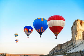 Fototapeta premium Colorful air balloons flying in clear sky near huge white mountain