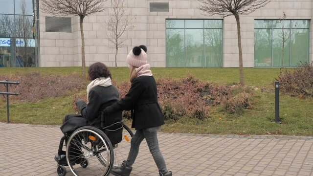 Spending time with relatives. Care and love. Mother in wheelchair with her little daughter spending time together outside.