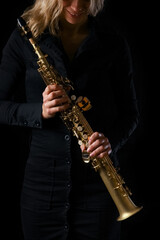 Fototapeta na wymiar soprano saxophone in the hands of a girl on a black background