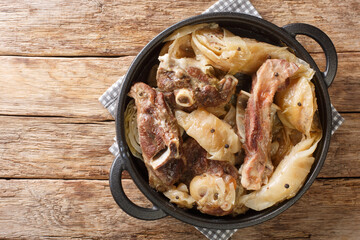 Norwegian cuisine lamb stew with cabbage and pepper in a pan on the table. Horizontal top view from above