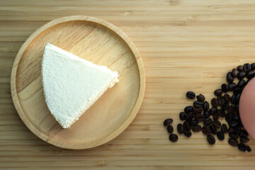 Piece of a creamy butter cake in wooden plate with coffee cup and egg for breakfast set. Homemade bakery concept for background and wallpaper.