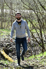 Fototapeta premium A bearded man walks through the spring forest.