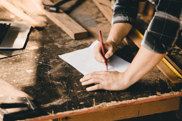 Carpenter hand drawing sketch design dream wooden furniture in paper in wood workshop table.