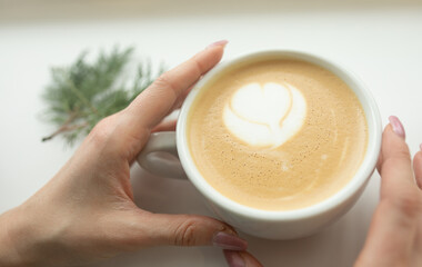 Close up of beautiful female hands holding big white cup of cappuccino coffee. Selective focus.