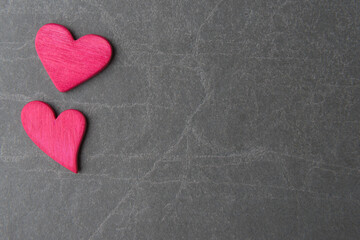 Obraz premium Two pink decorative hearts on grey stone background with copy space. Valentine’s day concept