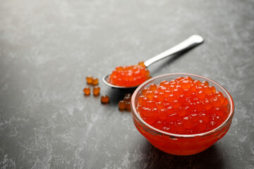 Glass bowl and spoon with caviar on black smokey background