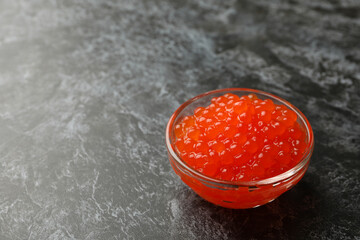 Glass bowl with caviar on black smokey background