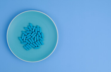 Similar pills lie on a blue plate. Blue background. The concept of victory over the coronavirus or vaccination. The end of the pandemic. Top view. Copy space text.