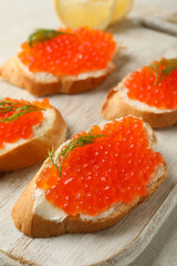 Wooden board with sandwiches with red caviar, close up
