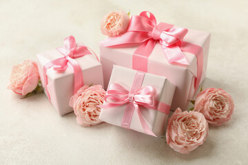 Gift boxes and roses on white textured background, close up