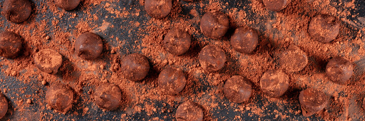 Chocolate truffles panorama. Many bonbons, shot from the top on a dark background