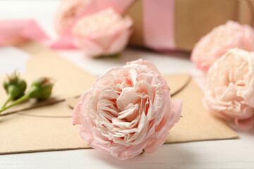 8 march concept with roses and envelopes on white wooden background