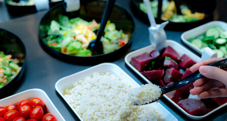 Hand holding spoon with boiled Job's tears at salad bar. Salad bar buffet at the restaurant. Fresh salad bar buffet for lunch or dinner. Healthy food. Catering food. Banquet service. Vegetarian food.